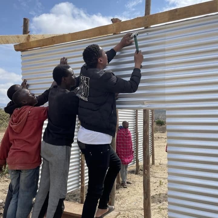 Young men nailing corrugated sheeting onto the frame of a new church