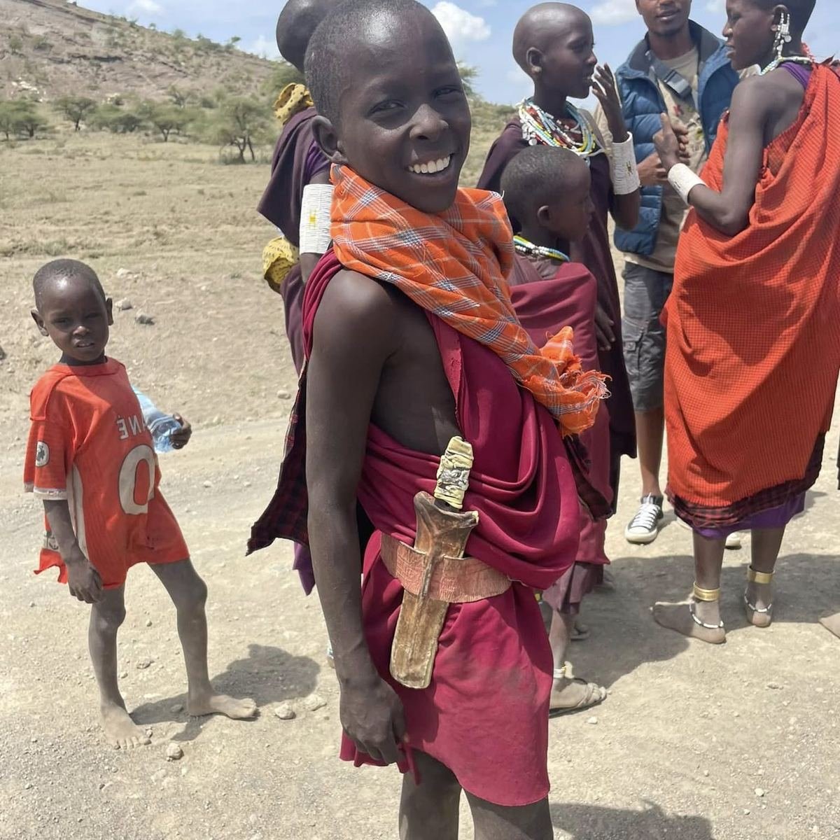 Maasai children in red and orange shukas gathered on the plains