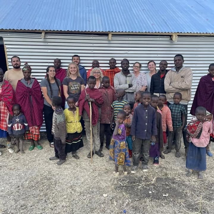 A large group of Maasai villagers gathered by a fence line