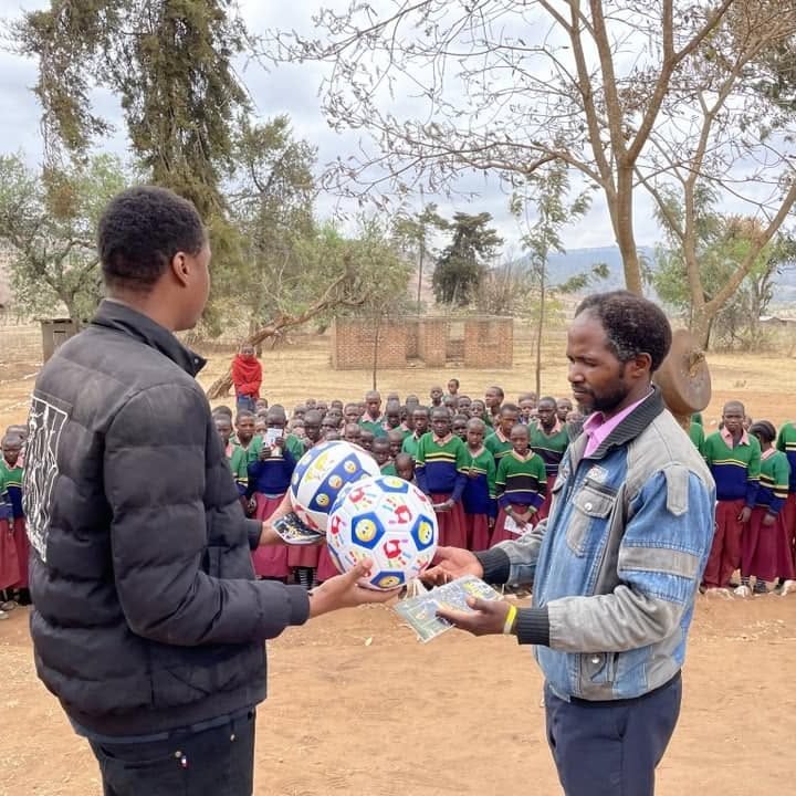 Two people handing over a parcel of supplies in a village