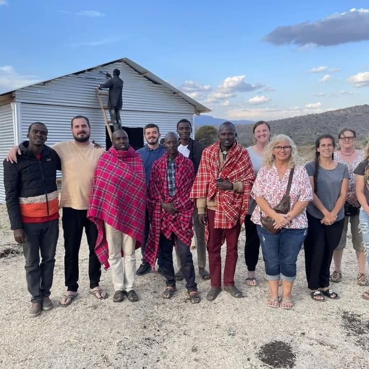 Mission team and Maasai men standing outside a nearly finished church